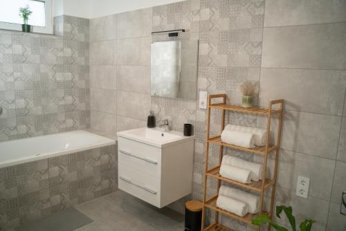 a bathroom with a sink and a tub and a mirror at Oázis Apartman in Zalakaros