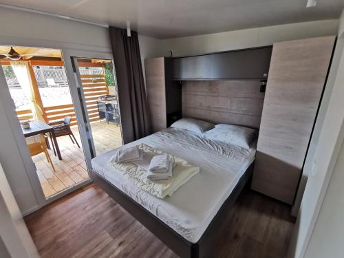 a bedroom with a bed and a balcony with a table at Mobile Home Happy Family Šimuni in Šimuni