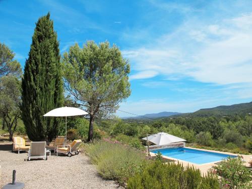 une piscine avec deux chaises et un parasol dans l'établissement Holiday Home Pascaire by Interhome, à Forcalqueiret