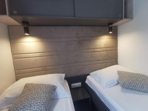 two beds in a room with a wooden headboard at Mobile Home Happy Family Šimuni in Šimuni