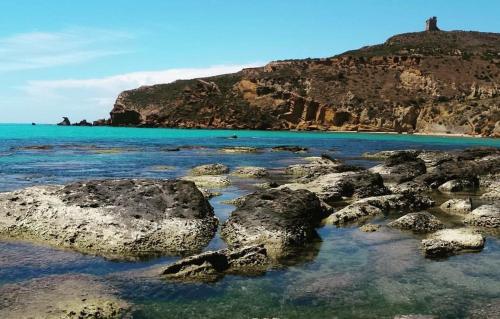 a beach with rocks in the water and a hill at La sKALunATa-Borgo di Kalat-Affitti brevi per uso turistico in Siculiana