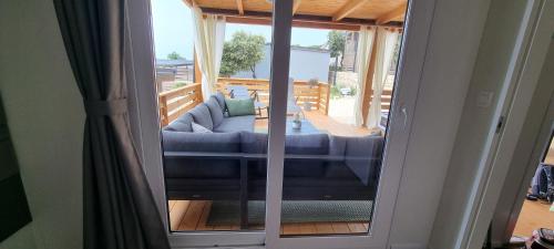 a sliding glass door with a couch on a porch at Mobile Home Happy Family Šimuni in Šimuni