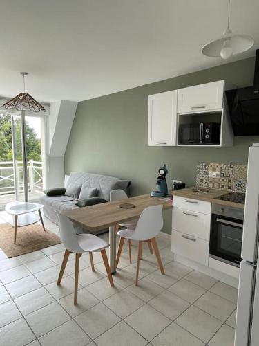 une cuisine et un salon avec une table et des chaises dans l'établissement Les Belles Rives T2 avec balcon ensoleillé, à Cabourg