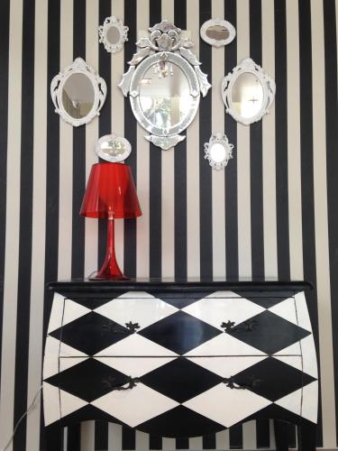 a table with a red lamp and mirrors on a striped wall at Ibis Styles Porto Alegre Centro in Porto Alegre