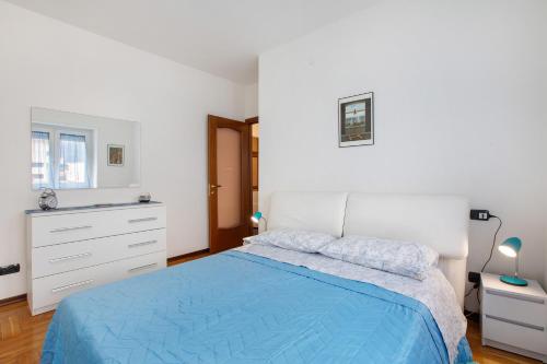 a white bedroom with a blue bed and a dresser at Casa Rosa Aosta in Aosta