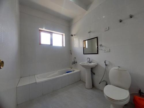 a white bathroom with a toilet and a sink at Smanla guest house in Leh