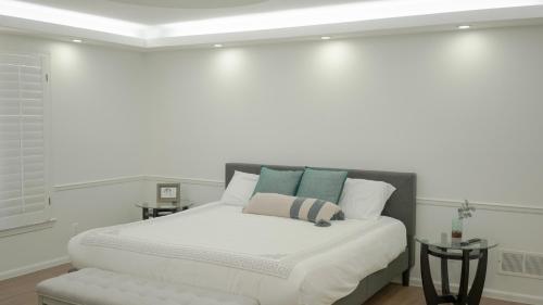 a white bedroom with a large bed and a stool at Casa Grande Luxur in Overland Park