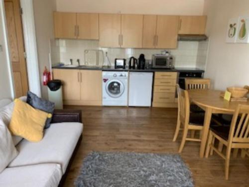 a living room with a couch and a table and a kitchen at Goodrington Lodge Holiday Apartments in Paignton