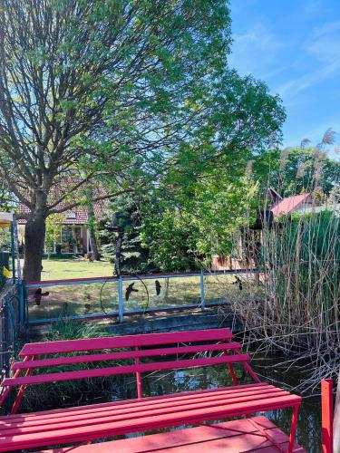 a red park bench sitting next to a fence at Vadvirág Apartmanház in Gyomaendrőd