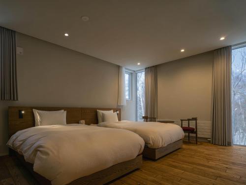 a bedroom with two beds and a table and a window at 山郷 Villas in Nature in Otaru