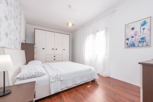 a white bedroom with a bed and a dresser at Apartman Mara in Poljica