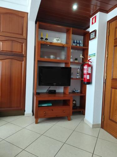 a living room with a television on a wooden entertainment center at Monte Gordo T1 - Estrela do Mar in Monte Gordo