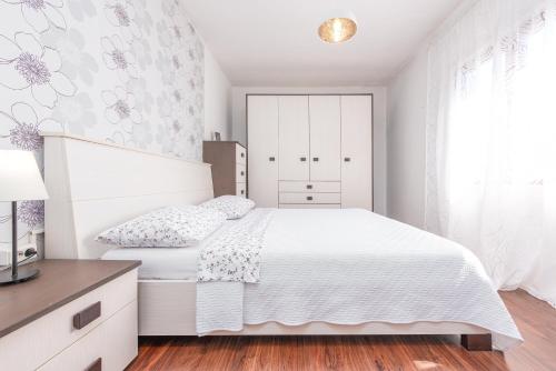 a white bedroom with a white bed and a window at Apartman Mara in Poljica