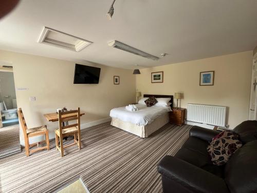 a bedroom with a bed and a table and a couch at Trimstone Manor Country House Cottages in Ilfracombe