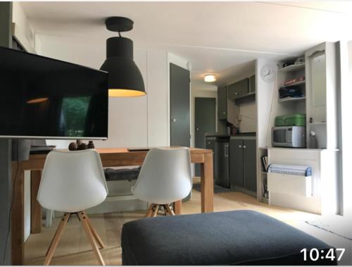 カストリクムにあるBeautiful tinyhouse sea dune and camping bakkumのリビングルーム(テーブル、白い椅子2脚付)