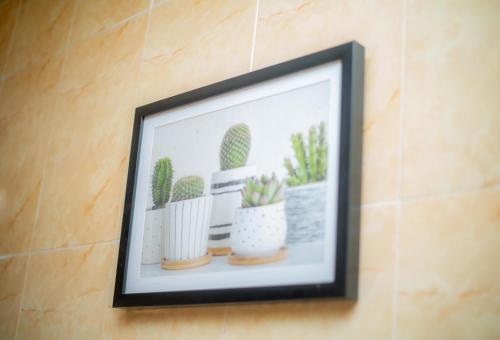 a framed picture of cactuses on a wall at Home Away from Home - Gowon Estate near Gemade, Ipaja, Lagos in Lagos