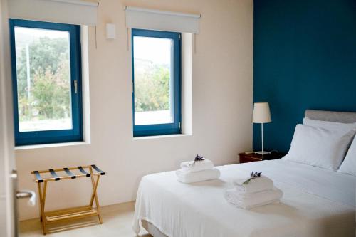 a bedroom with two towels on a bed with two windows at Charming Vourkari Stone Home 1 - Minutes from port in Vourkari