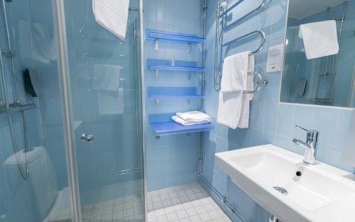 baño azul con ducha y lavamanos en Ramundbergets Fjällgård en Ramundberget