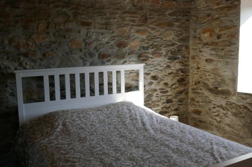 une chambre avec un lit dans un mur de pierre dans l'établissement Casa Escola Velha, à Vale de Cameiro