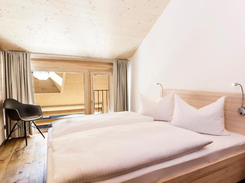 ミッテルベルクにあるalpen select apartments Kleinwalsertalのベッドルーム(大きな白いベッド、椅子付)