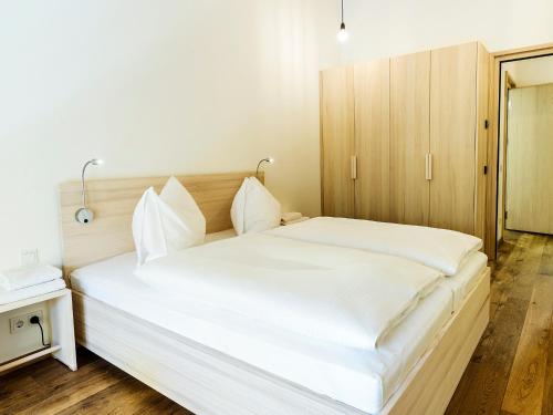 ミッテルベルクにあるalpen select apartments Kleinwalsertalの白いシーツが敷かれた大きなベッドのある寝室