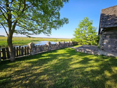an old house with a fence next to a lake at Filipówka in Sztabin
