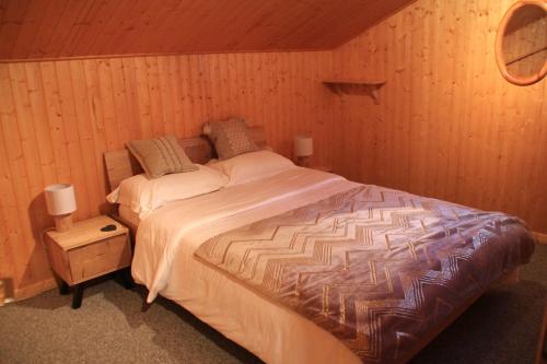 - une chambre avec un grand lit dans un mur en bois dans l'établissement Chalet Ecureuil ECR CHARMING & NATURE 5 Pers, à Châtel