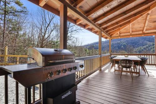 a grill on a deck with a table and chairs at The Remedy at Blue Ridge - mountain view cabin with hot tub and two fire pits in Cherry Log