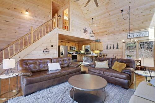 a living room with leather furniture and a staircase at The Remedy at Blue Ridge - mountain view cabin with hot tub and two fire pits in Cherry Log