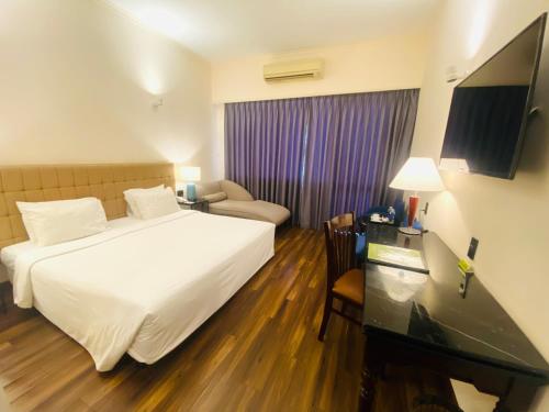 a hotel room with a white bed and a desk at Liberty 2 Hotel in Ho Chi Minh City
