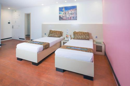 a bedroom with two beds and a pink wall at Eurotel Pedro Gil in Manila