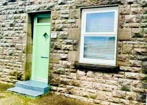 a building with a green door and a window at Quaint cottage close to Marina in Pembrokeshire