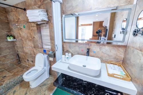 a bathroom with a sink and a toilet and a mirror at Lijiang Old Town Meiliju View Inn in Lijiang