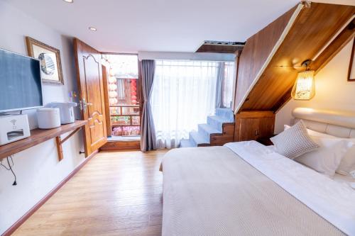 a hotel room with a bed and a television at Lijiang Old Town Meiliju View Inn in Lijiang