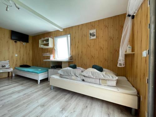 a bedroom with a bed with wooden walls and a window at Łąkowa Dolina - domek letniskowy in Supraśl