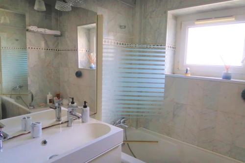 une salle de bain avec un lavabo, une baignoire et un miroir dans l'établissement Superbe appartement à Paris, à Puteaux
