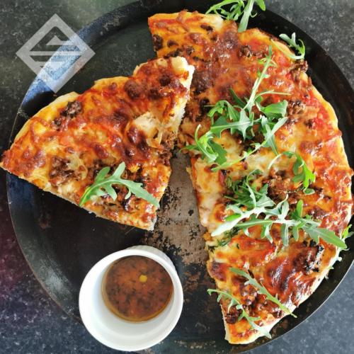 two slices of pizza on a plate with sauce at Plas y Brenin - National Outdoor Centre in Capel-Curig