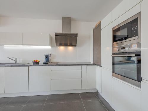 une cuisine blanche avec des armoires blanches et un micro-ondes dans l'établissement Apartment Le Newport-3 by Interhome, à Fréjus