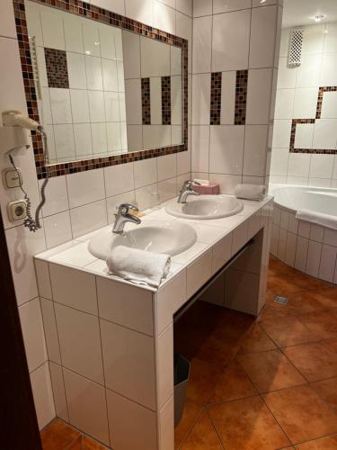 La salle de bains est pourvue de 2 lavabos et d'un grand miroir. dans l'établissement Vintagehotel Adler, à Bad Bertrich