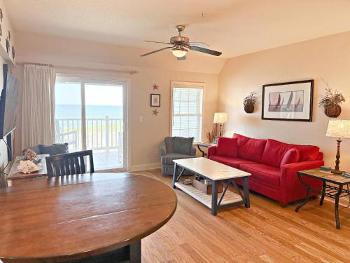 a living room with a red couch and a table at FF215 First Flight Retreat 215 in Kill Devil Hills