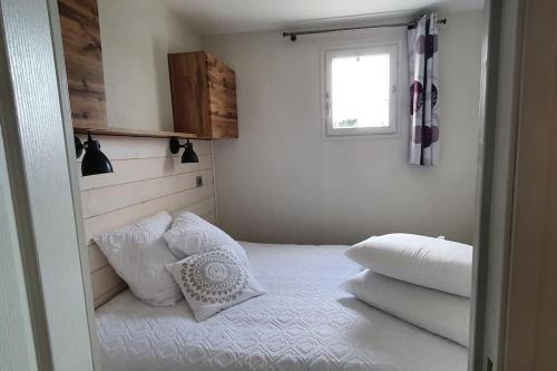 une chambre avec un lit avec des oreillers blancs et une fenêtre dans l'établissement A l'Orée des Pins, Appartement Plage du Tanchet, à La Pironnière