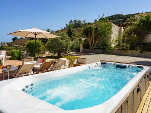 a large swimming pool with chairs and an umbrella at Holiday Home Camelia Blanca by Interhome in Torrox