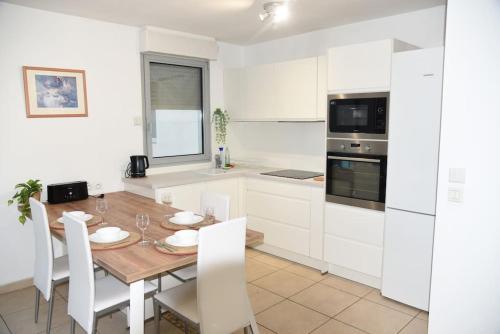 une cuisine avec une table en bois et des armoires blanches dans l'établissement Proche Montpellier, T3, 2 chambres, parking, tram, à Castelnau-le-Lez