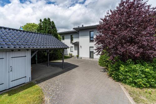 a white house with a garage and a tree at Ferienvilla Kapitänshaus in Ostseebad Karlshagen