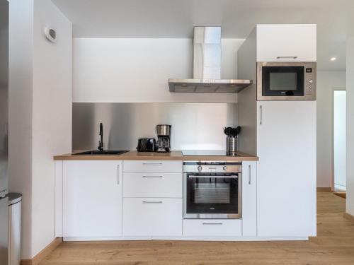 une cuisine avec des armoires blanches et un micro-ondes dans l'établissement Apartment Le Zodiaque II-4 by Interhome, à Hyères