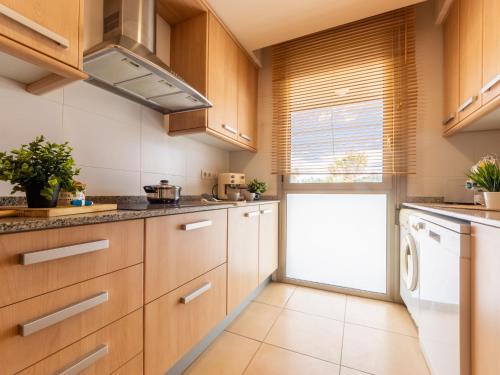a kitchen with wooden cabinets and a washer and dryer at Apartment Viena 13 by Interhome in L'Ampolla