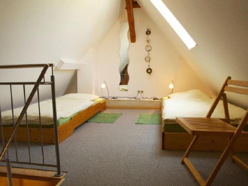sypialnia na poddaszu z 2 łóżkami i krzesłem w obiekcie Winzerhof Bitzenhofer w mieście Vogtsburg im Kaiserstuhl