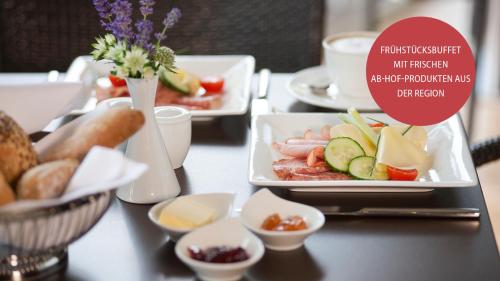 a table topped with plates of food on a table at Heilthermen Resort Bad Waltersdorf in Bad Waltersdorf