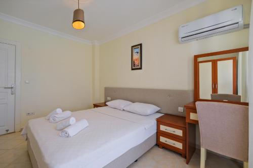 a bedroom with a bed with white sheets and a desk at Larimar Suite Hotel in Oludeniz