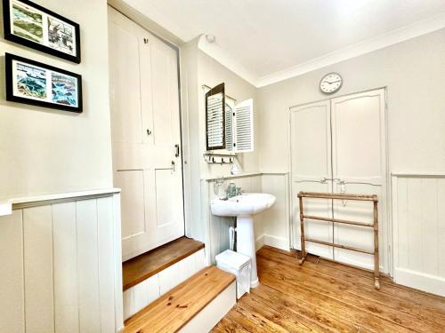 a white bathroom with a sink and a mirror at Zeta Cottage in Ryde